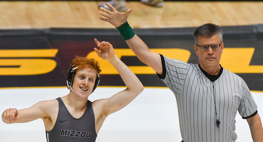 An official lifts Allan Hart's hand after his victory over Caleb Brooks in the 133 pound weight class